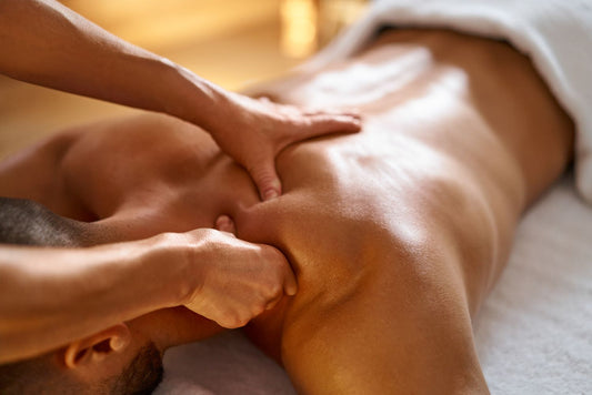 Exploring the Magic of Myofascial Release: A Journey to Wellness. A young man laying facedown on a massage table while the massage therapist massages his shoulder.