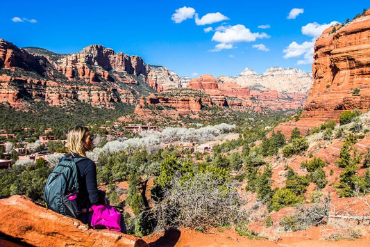 Beyond the Physical: The Essence of Sedona's Spiritual Vortexes. A young women sitting on a red rock looking at the view of Boynton Canyon.