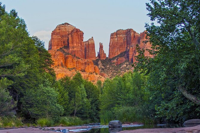 Nature's Gift: Unveiling the Different Types of Spiritual Vortexes in Sedona. This image is a view of Sedona's most iconic red rock formation called Cathedral Rock taken from Oak Creek surrounding the base of the image with trees.