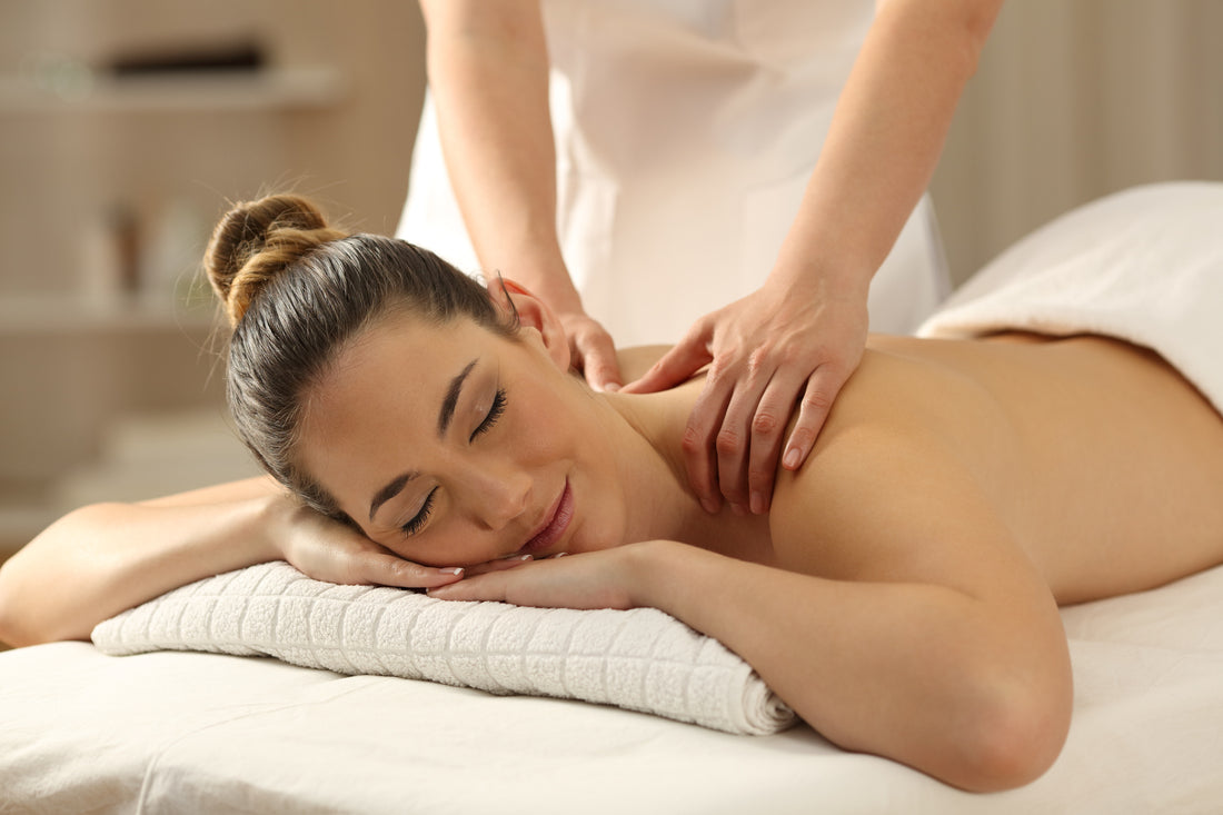 Revitalize Your Body with Sports & Orthopedic Massage. A young woman laying face down on a massage table while a massage therapist works on her shoulders.