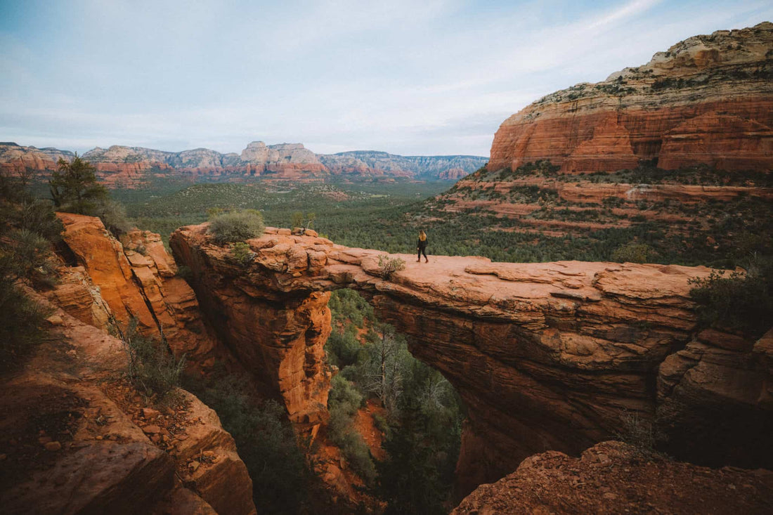 Hiking in Sedona: Tips & Tricks. A person walking accross the Devil's Bridge natural formation in the back country of Sedona.