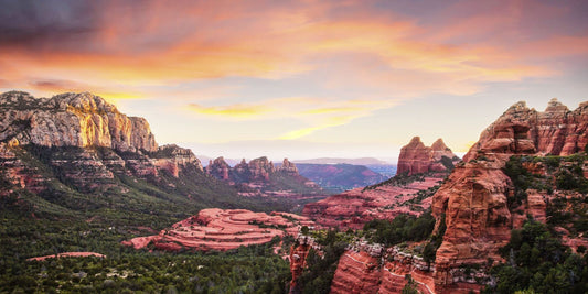 Unlocking the Mysteries: Exploring Sedona's Spiritual Vortexes. This image looks over the Sedona red rock formations at sunset with orange clouds