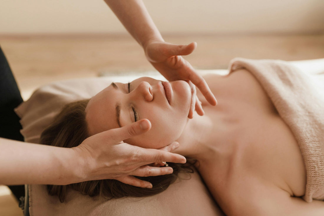 Rejuvenate and Detoxify with Lymphatic Drainage Massage. A young woman face up on a massage table with the massage therapists hands under her jaw