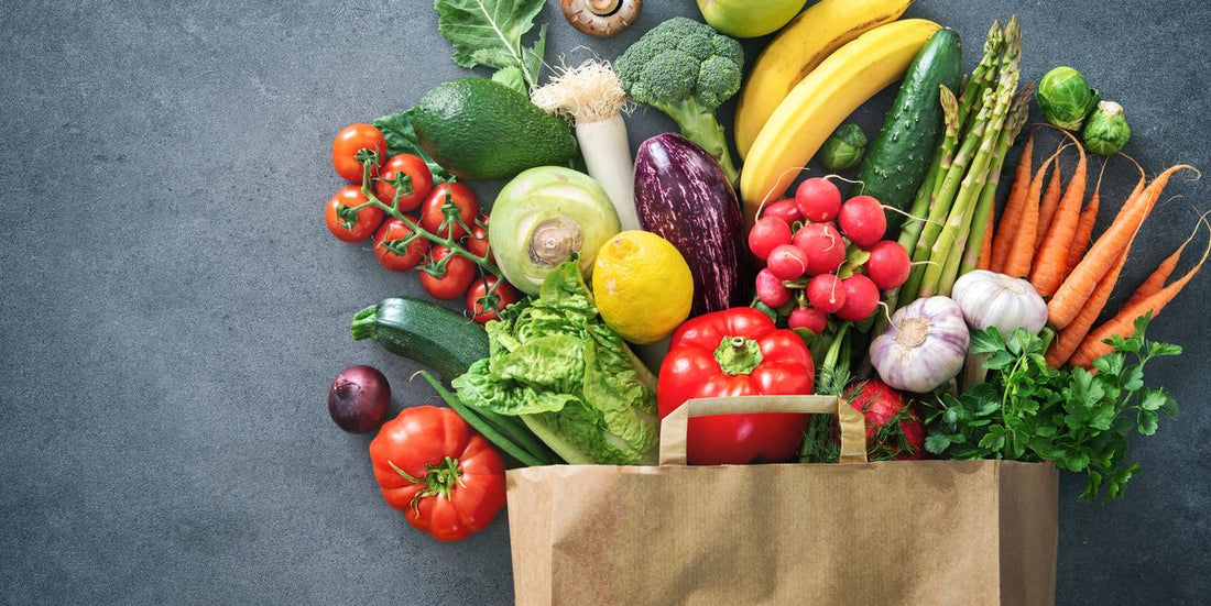 Health-Conscious Choices: Optimal Wellness with Sedona Grocery Delivery. This image is of fruits and vegetables spilling out of a paper grocery bag onto a grey countertop